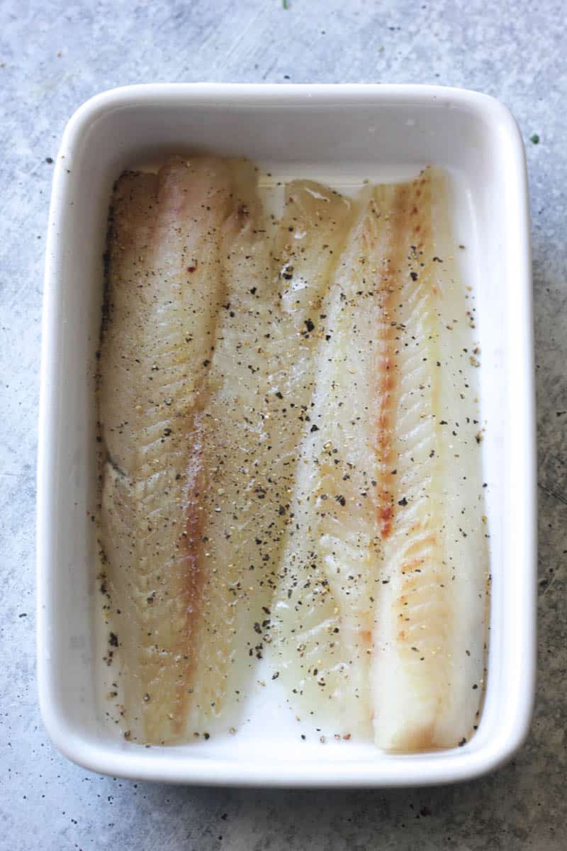 raw seasoned pollock fillets in the white baking dish