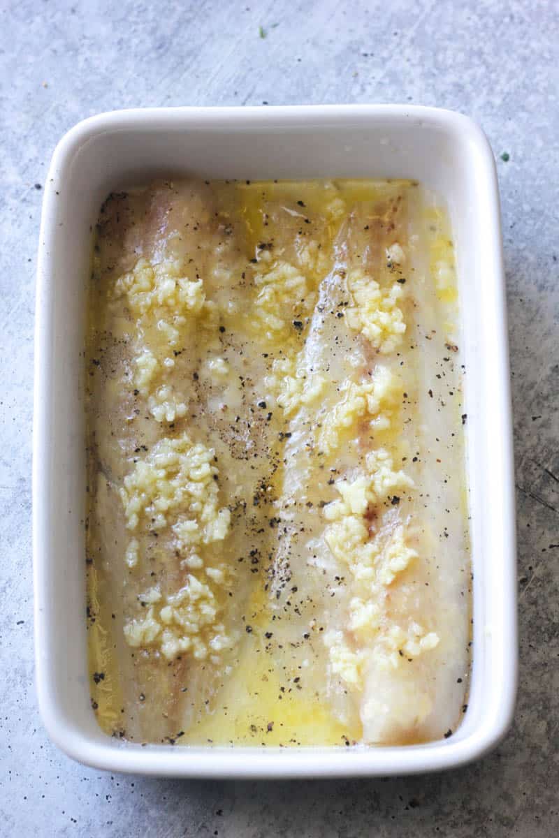 white fish fillets covered in chopped garlic and olive oil
