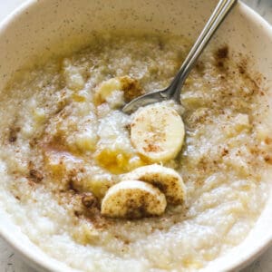 banana grits in a bowl with sliced bananas on top