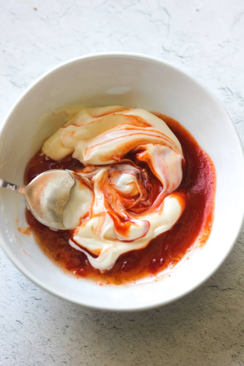mixing mayo with red sauce in a small bowl