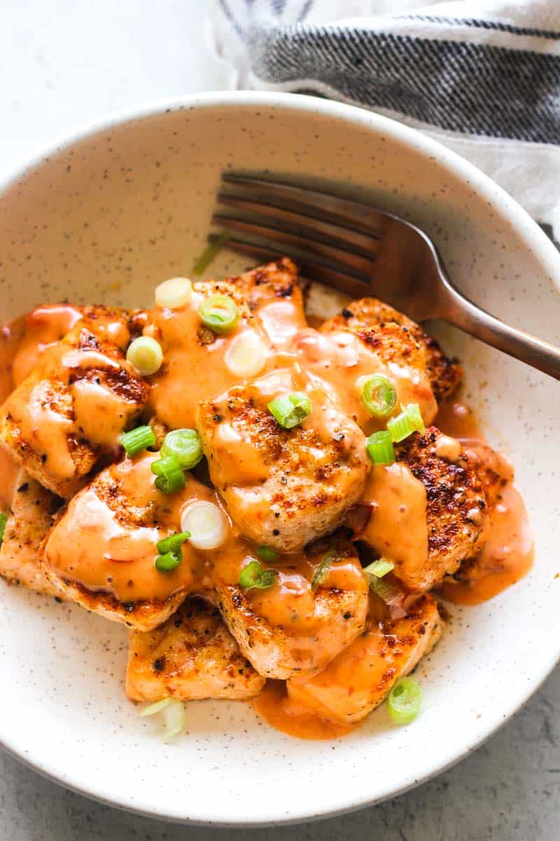bang bang salmon bites in the bowl with green onions on top