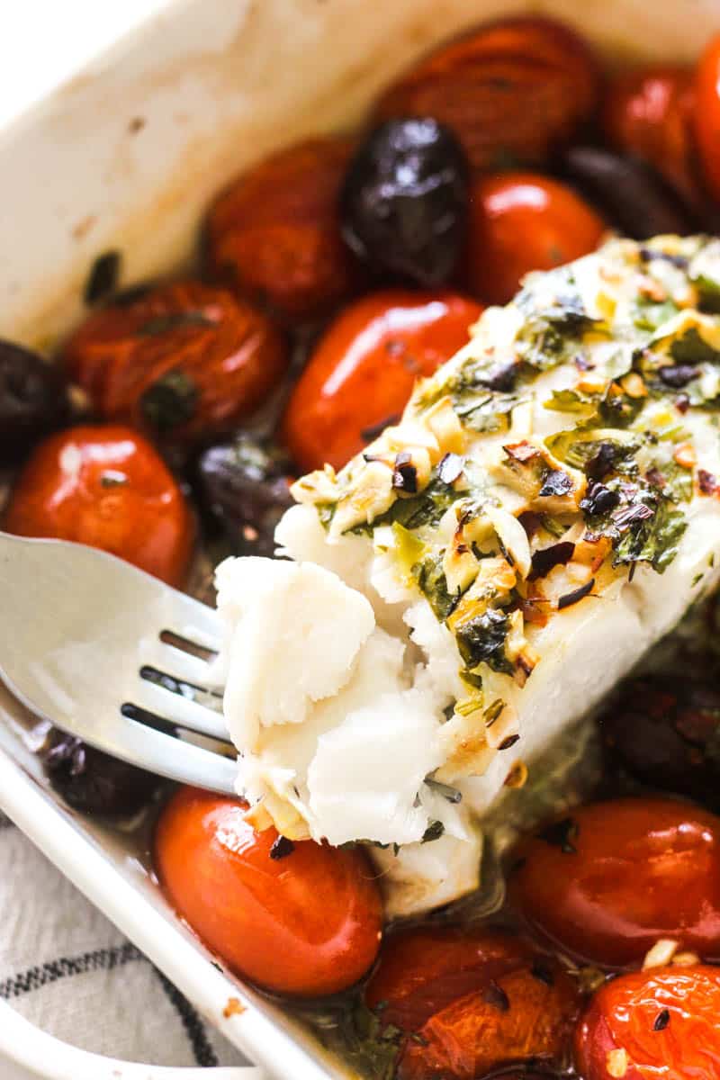 hake fillet bite on the fork with black olives and tomatoes