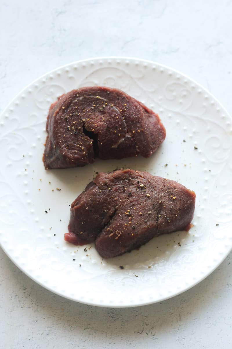 raw seasoned ostrich steaks on the white plate