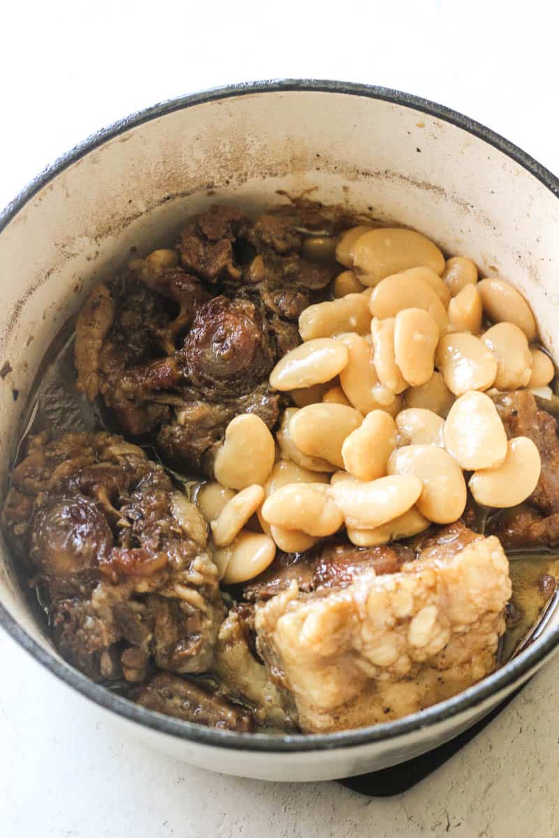 butter beans on top of cooked beef in the white pot