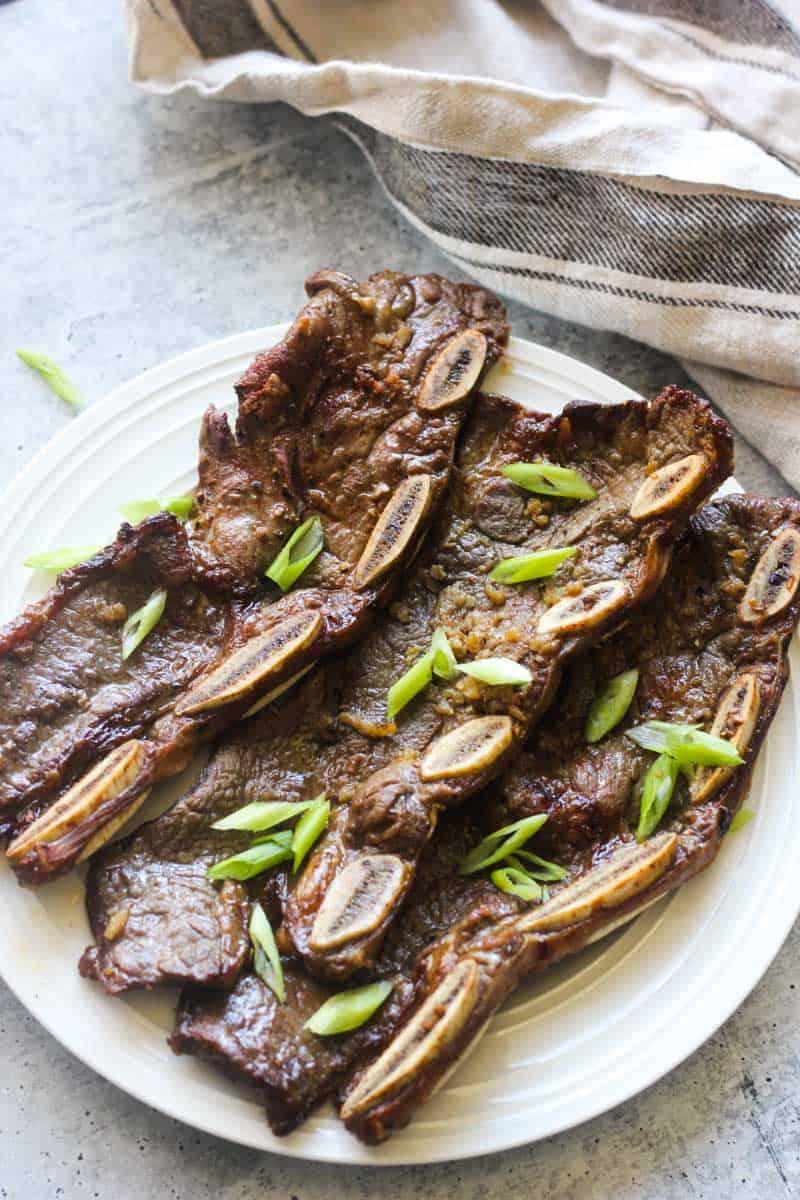 pulehu ribs on a white plate with chopped green onions on top