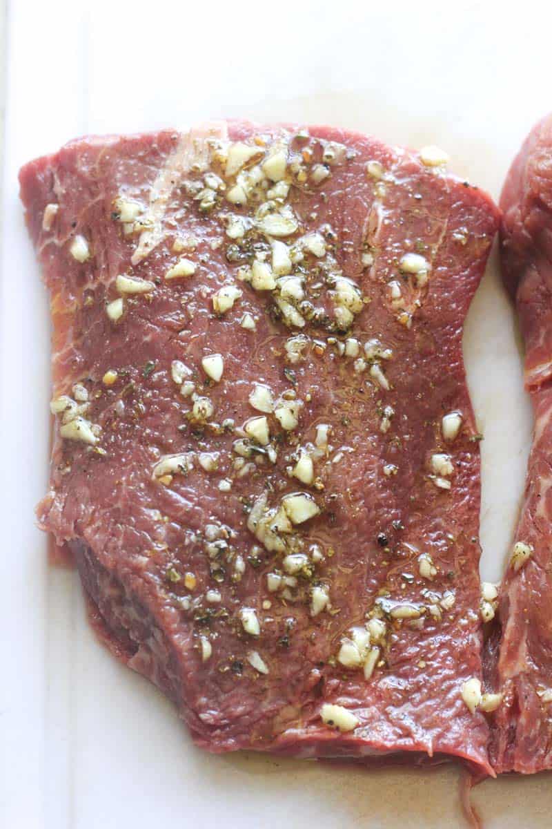 seasoned piece of red meat on white cutting board
