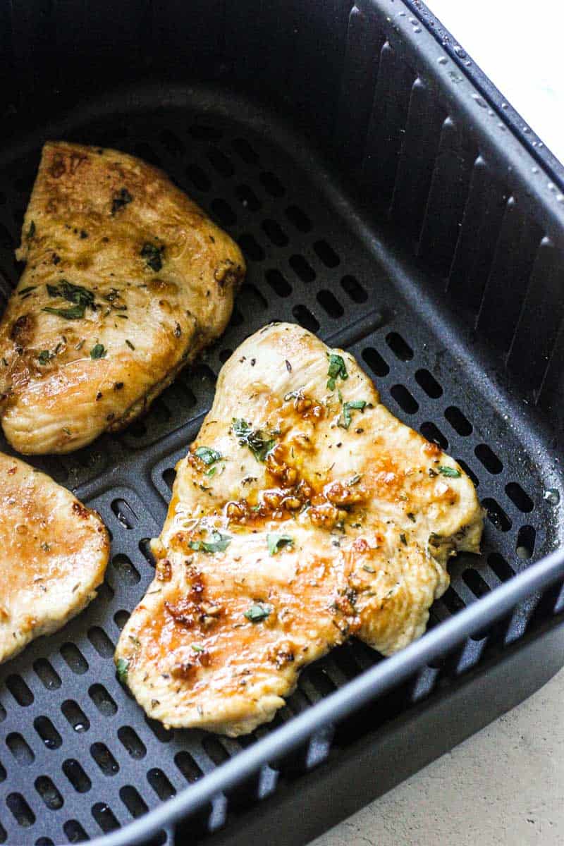 turkey steaks in air fryer basket with chopped cilantro on top