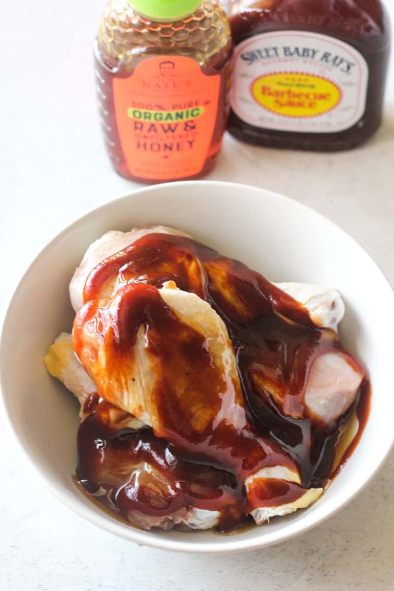chicken drumsticks covered with brown bbq sauce sauce in a white bowl