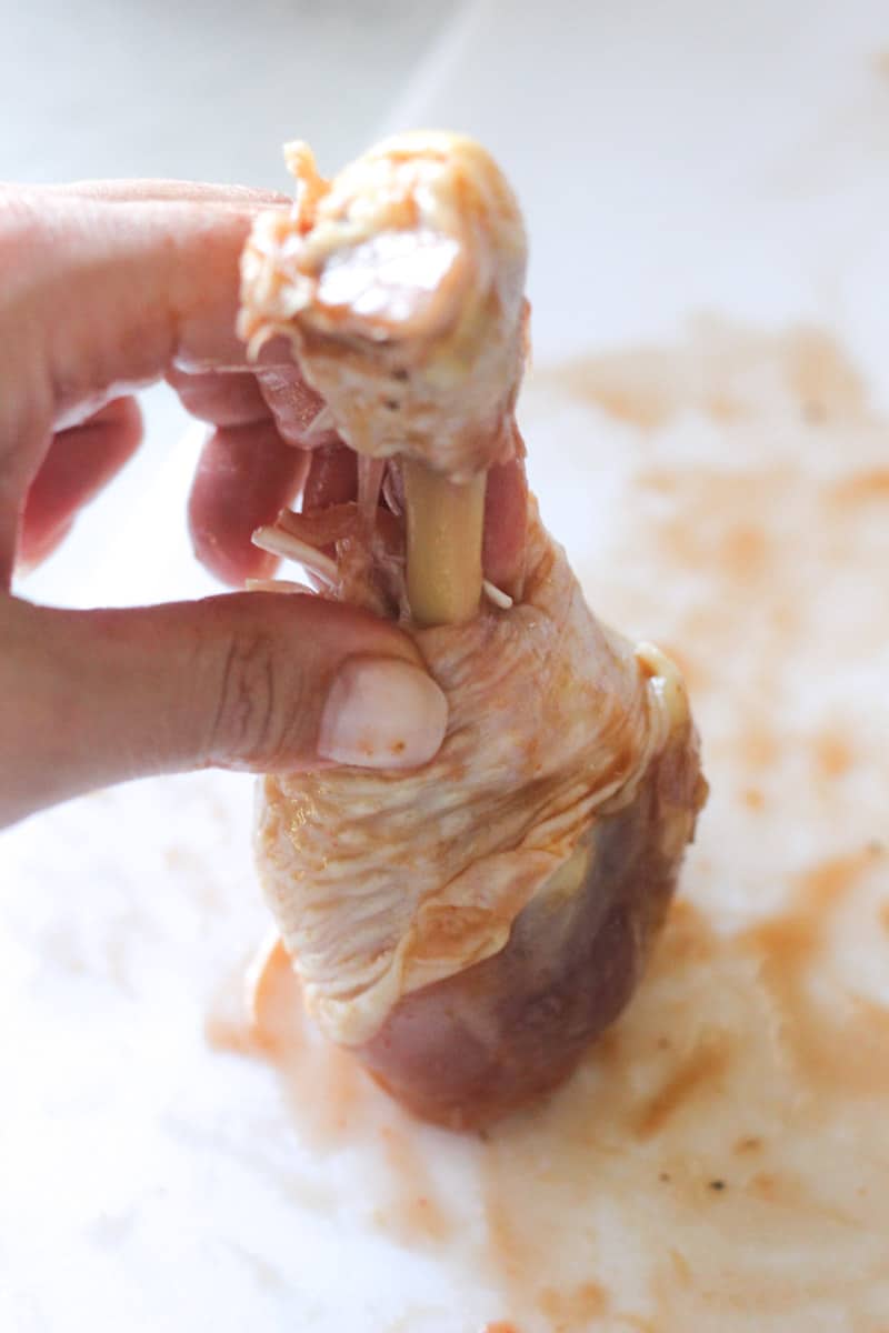 making a chicken lollipop out of chicken leg on the cutting board