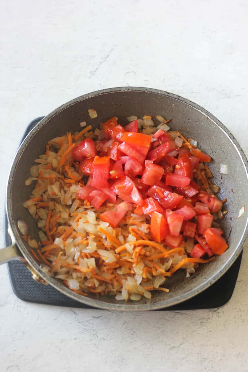 chopped tomatoes, onions and carrots in the pan