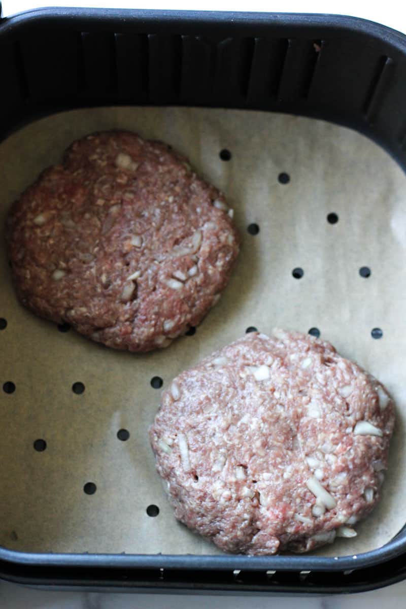 two bison burgers in air fryer before cooking