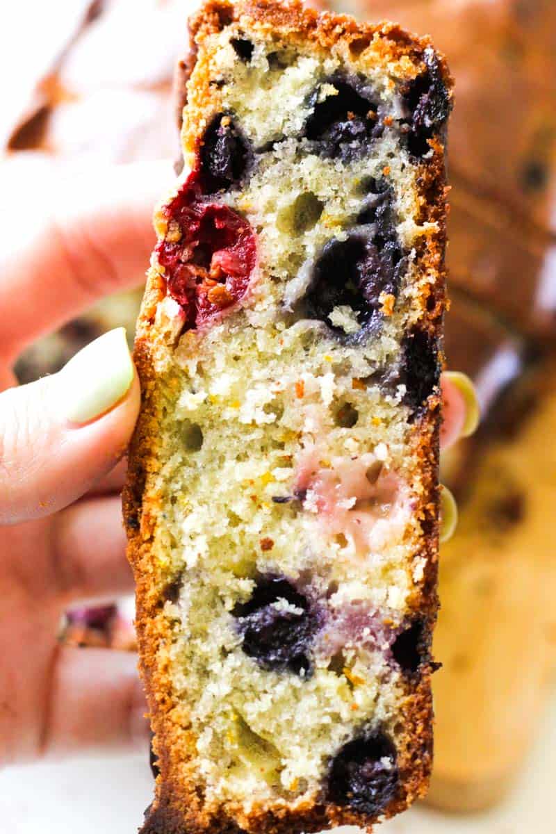a slice of cranberry blueberry bread in hand