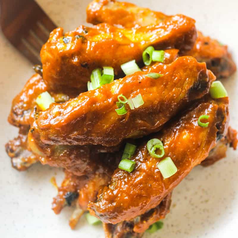honey gold wing sauce on chicken wings with chopped green onions on top