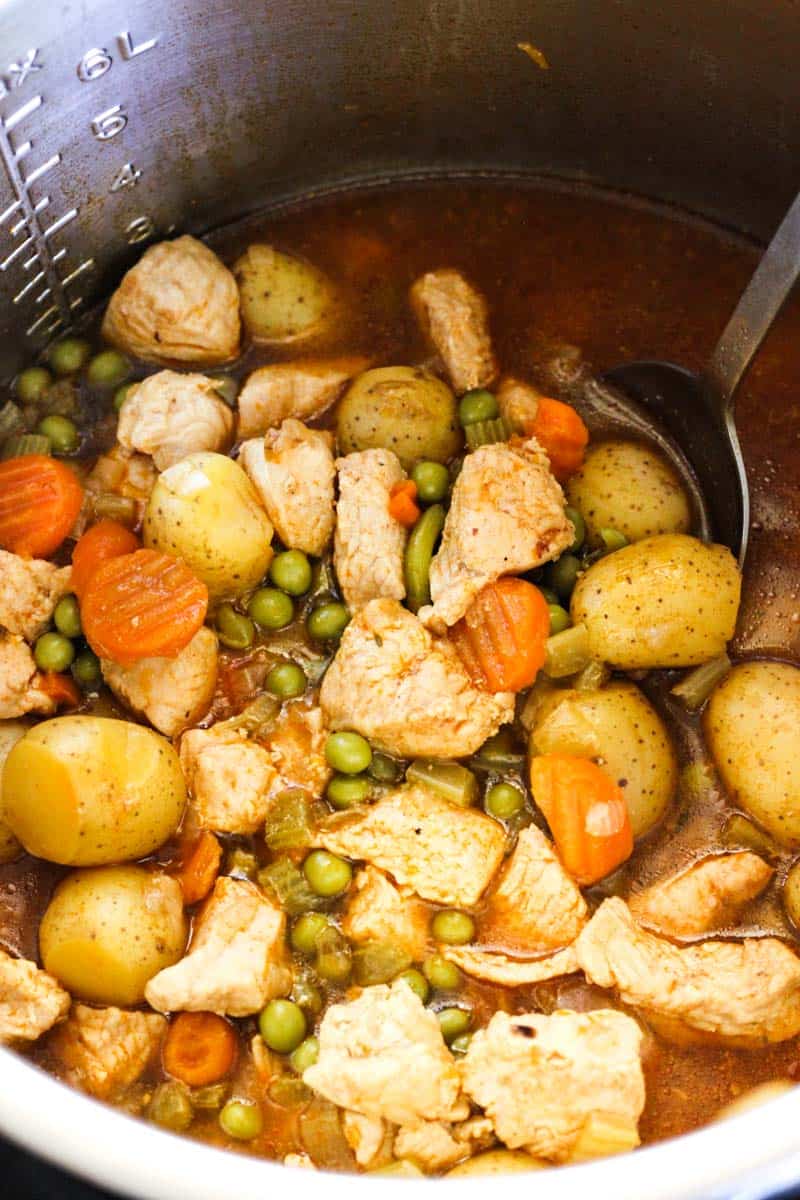 instant pot turkey stew with peas, carrots and potatoes in a inner pot with broth, top view
