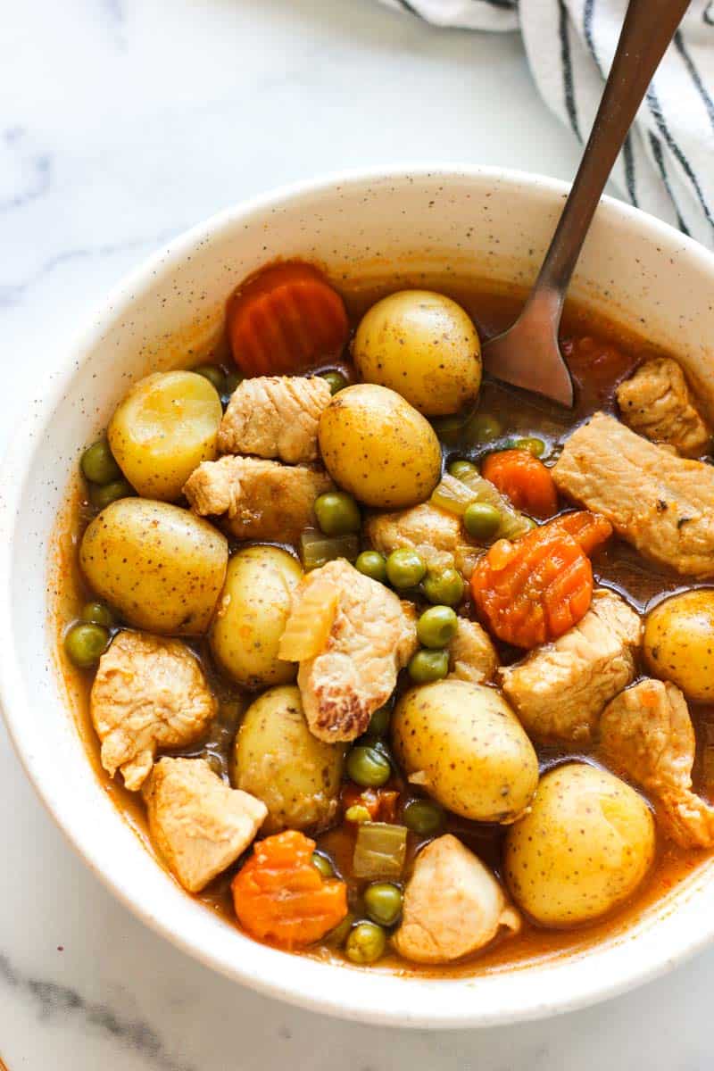 turkey pieces with peas, carrots and potatoes in a bowl with broth, top view