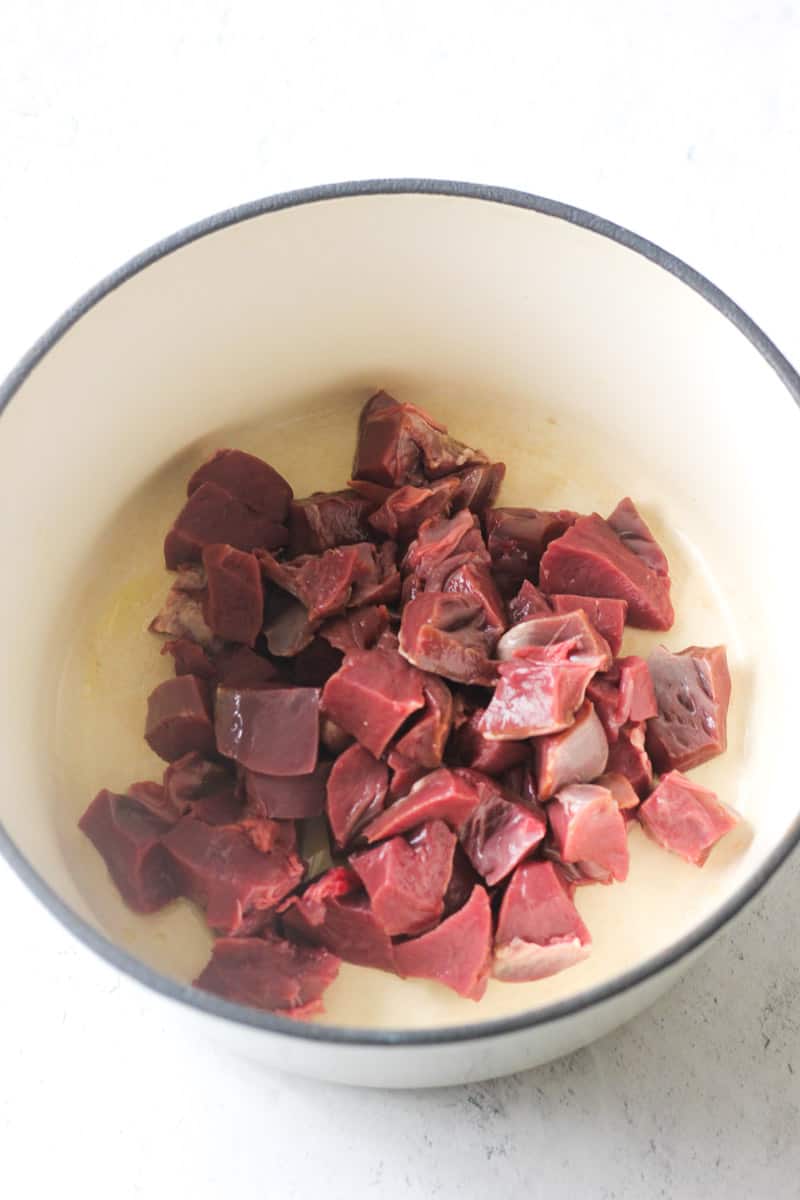 raw chopped pork heart in a pot before cooking