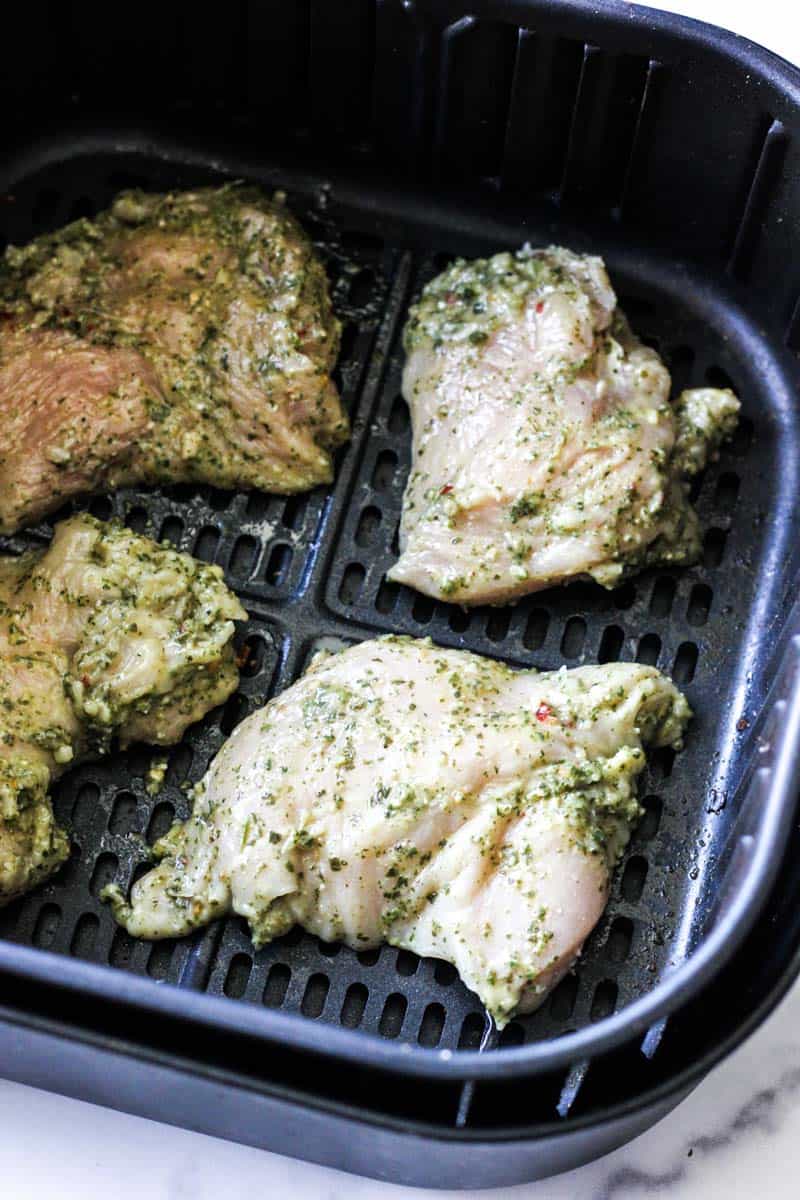 raw chicken breast pieces with pesto sauce in the air fryer