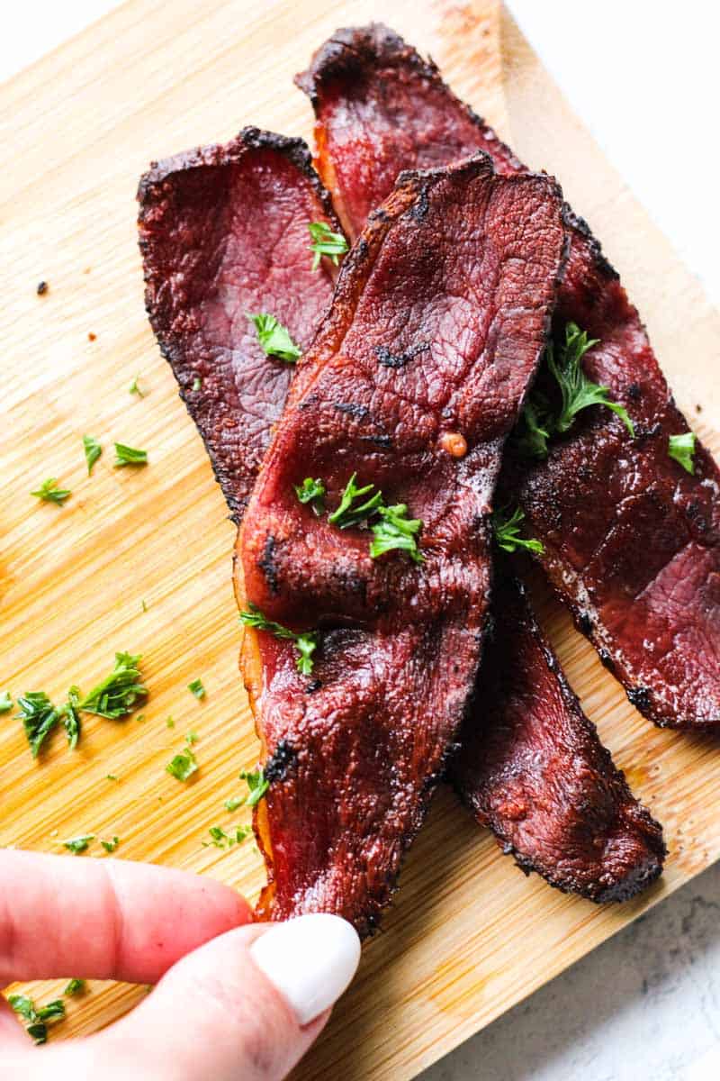 cooked crispy duck bacon on a cutting board