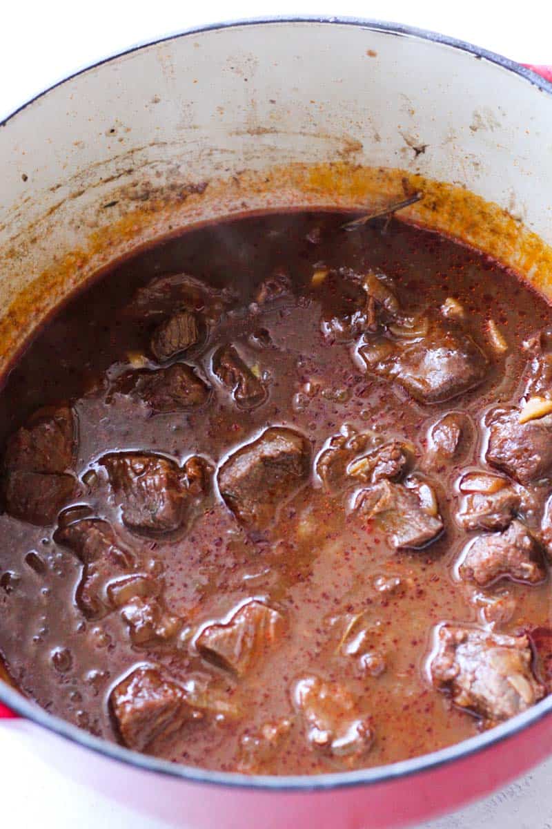 brown broth for elk stew with elk pieces in it