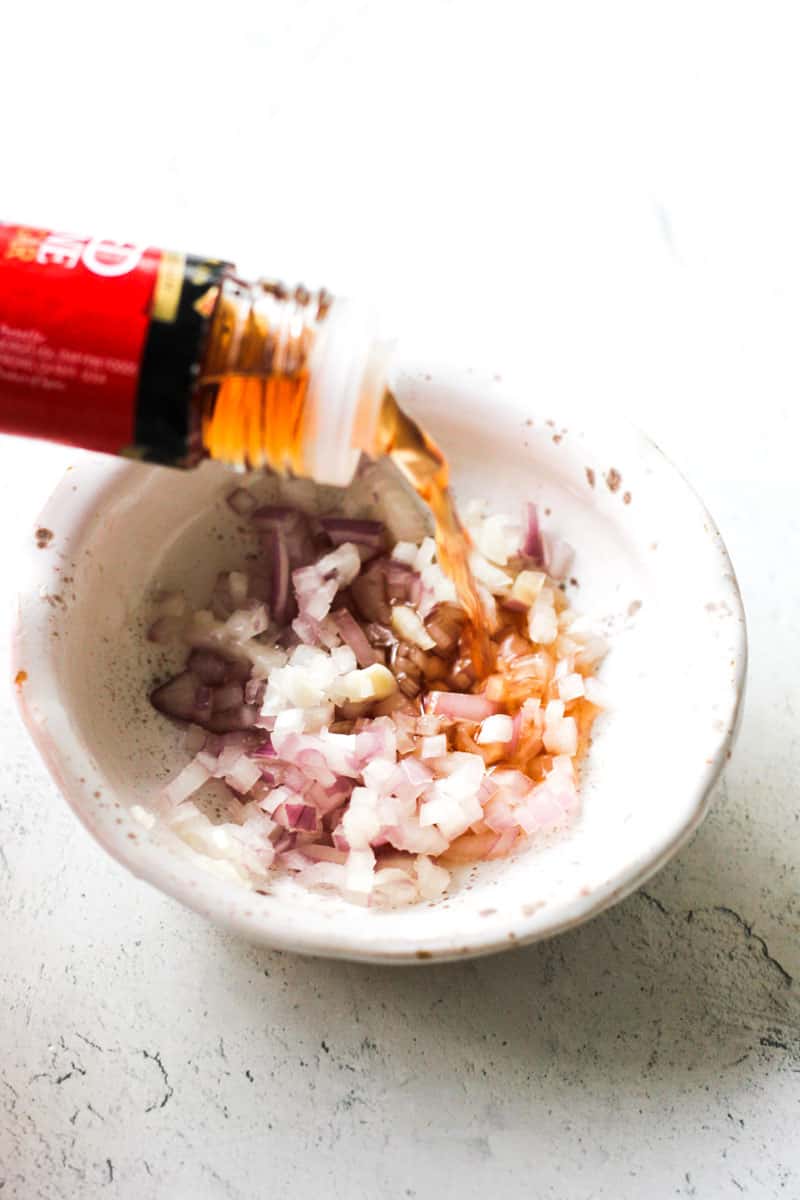 pouring red wine vinegar in to the bowl with chopped shallots