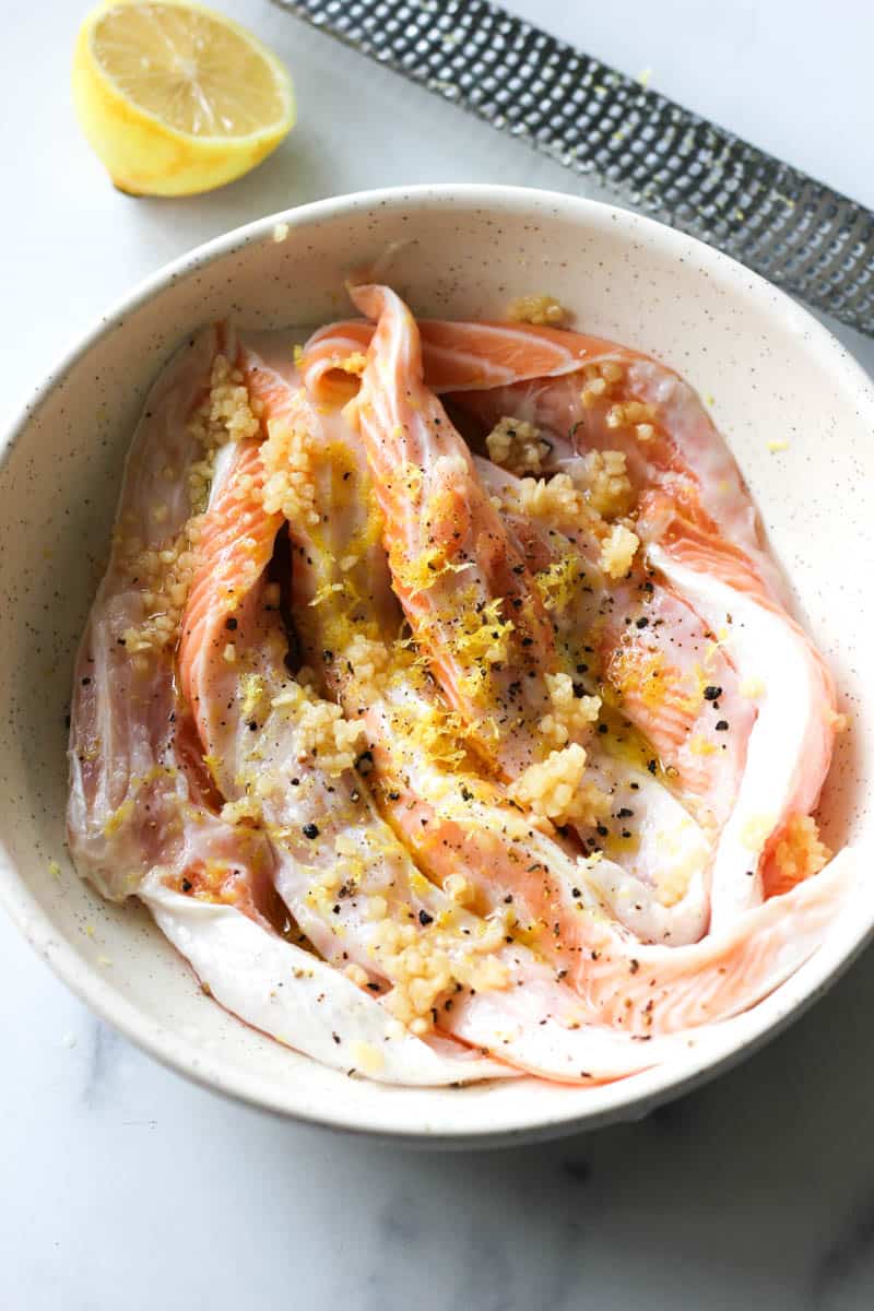 seasoned raw salmon belly in the bowl with lemon zest