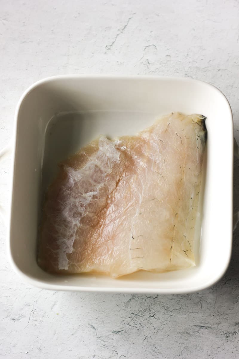 raw walleye fillet in the white baking dish