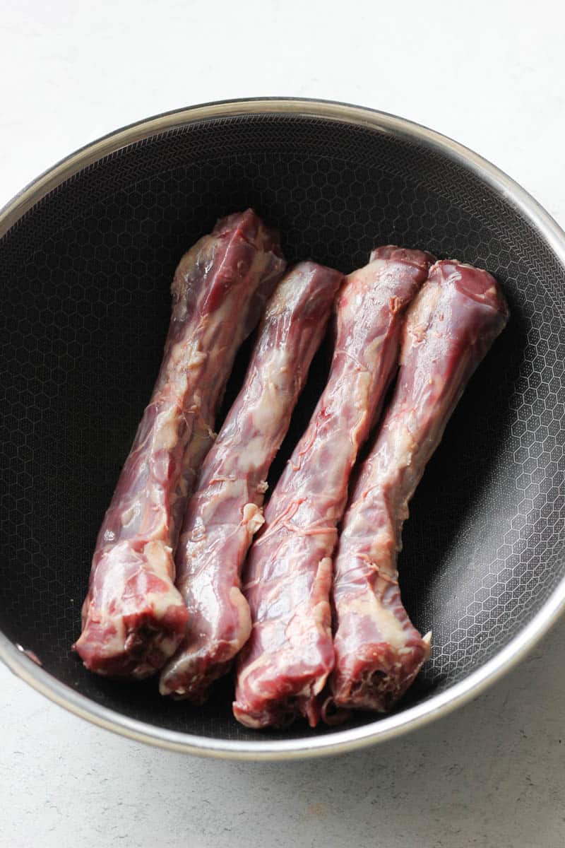 four raw duck necks in the skillet