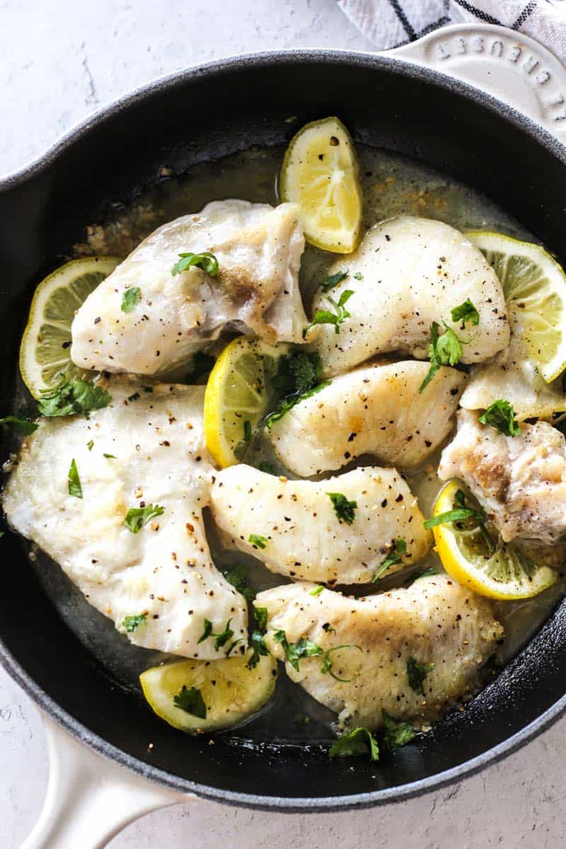 pan seared halibut cheeks with lemon slices in cast iron skillet