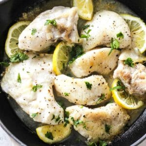 pan seared halibut cheeks with lemon slices in cast iron skillet