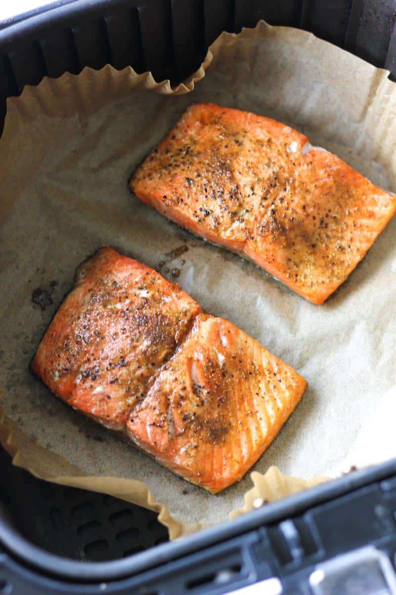 cooked old bay salmon in air fryer topped with parchment paper