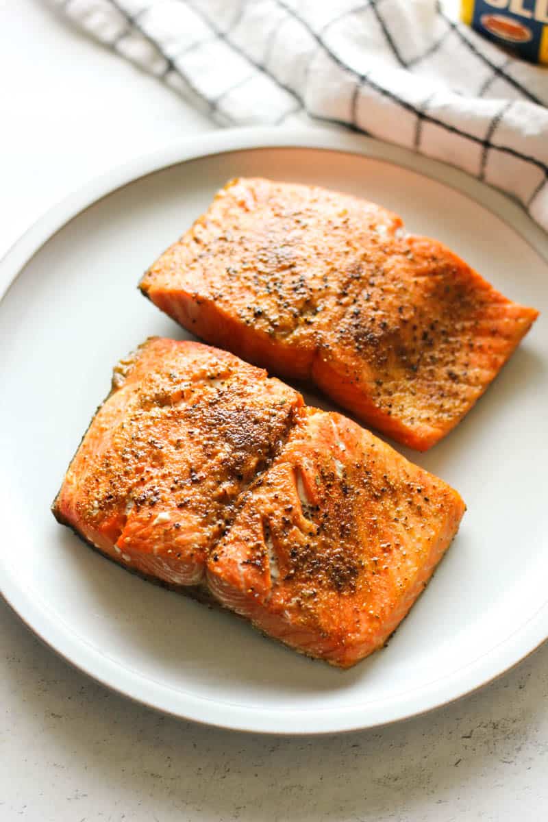 two pieces of salmon seasoned with old bay seasoning on top of grey plate