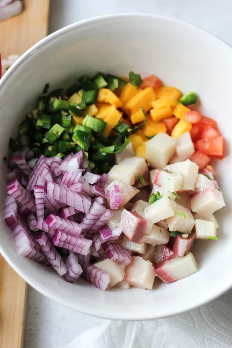 chopped veggies and mango in the white bowl