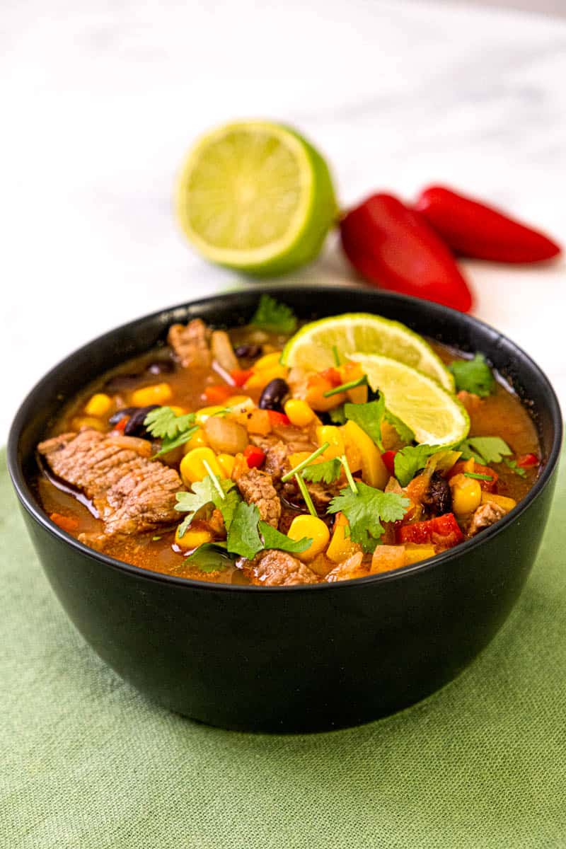 carne asada soup in the black bowl