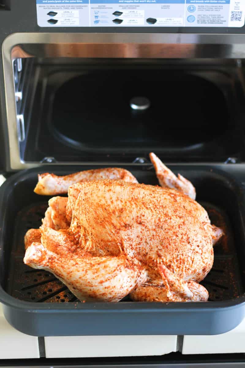 raw seasoned whole chicken in the tray