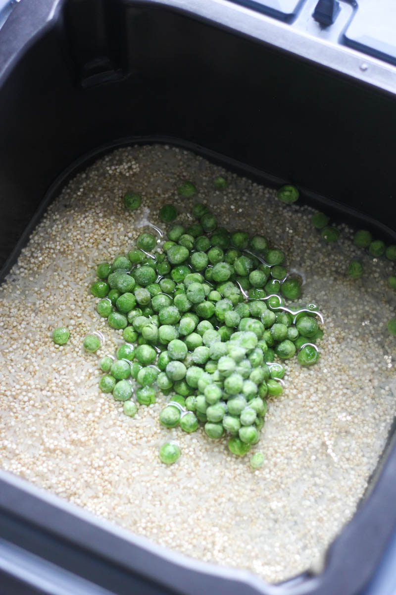 rice and quinoa with frozen green peas on top in the pot