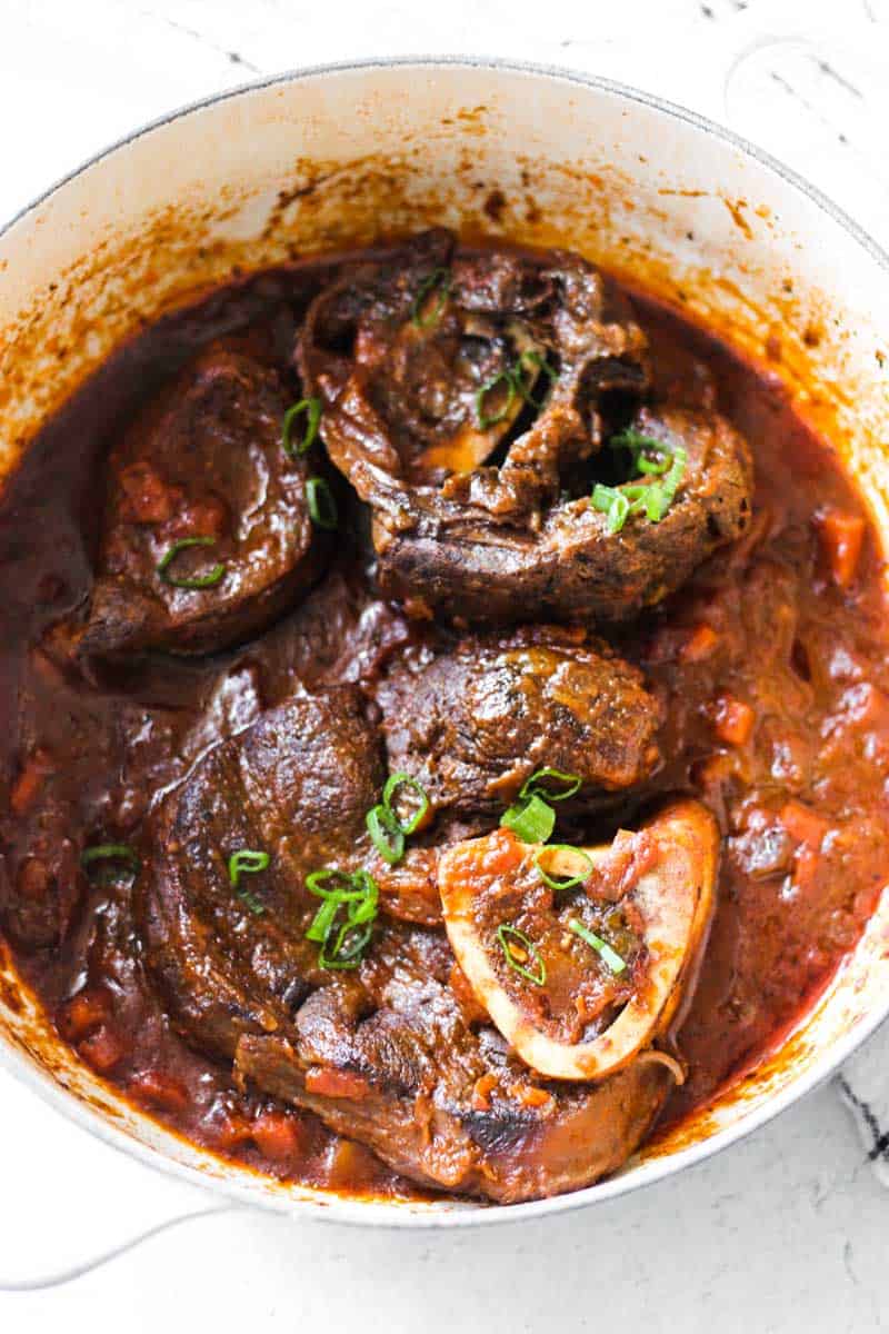 bison osso buco in the pot with chopped green onions on top