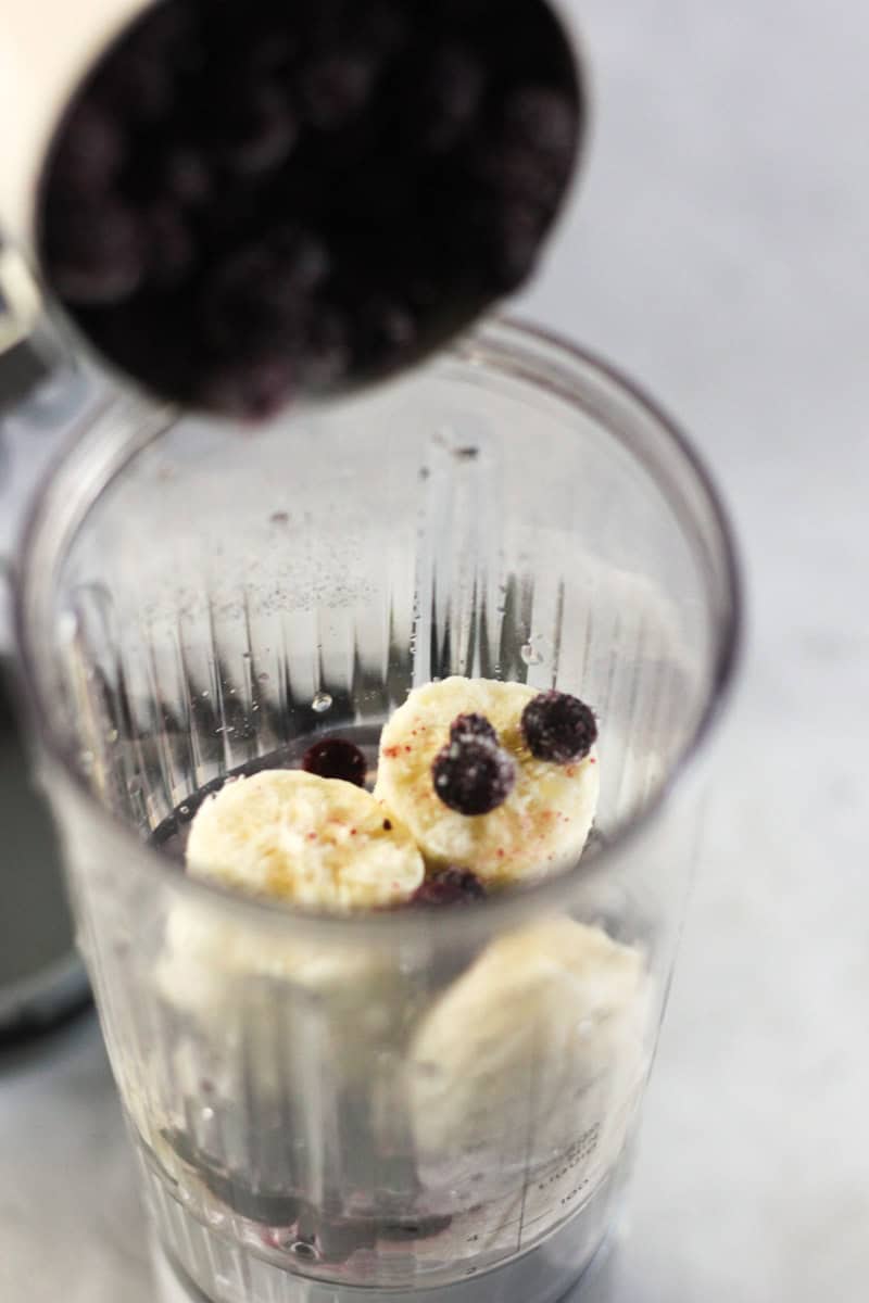 bananas and frozen blueberries in the blender jar