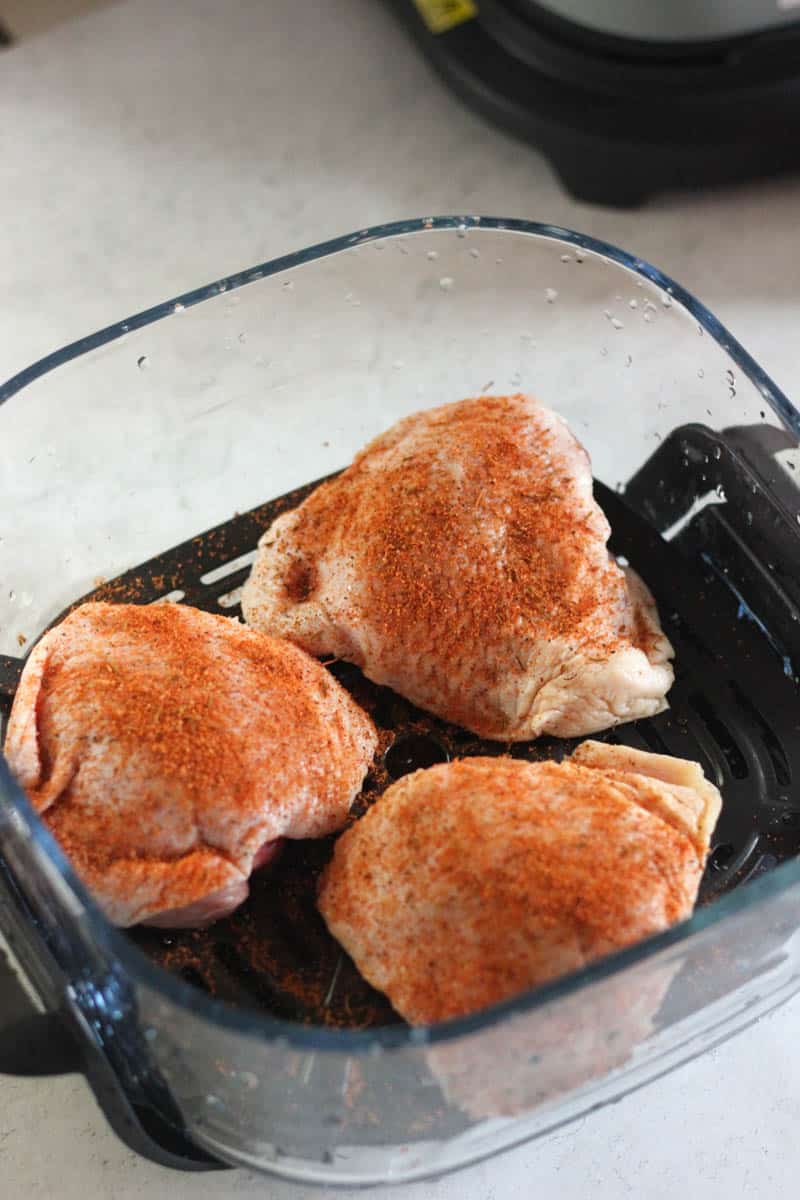 raw chicken thighs with seasoning in the glass container