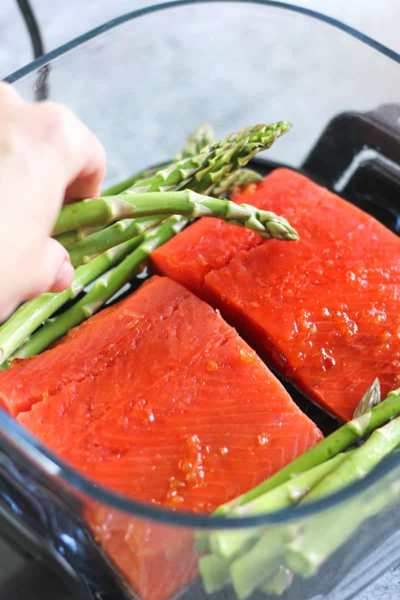 adding asparagus to raw salmon in air fryer