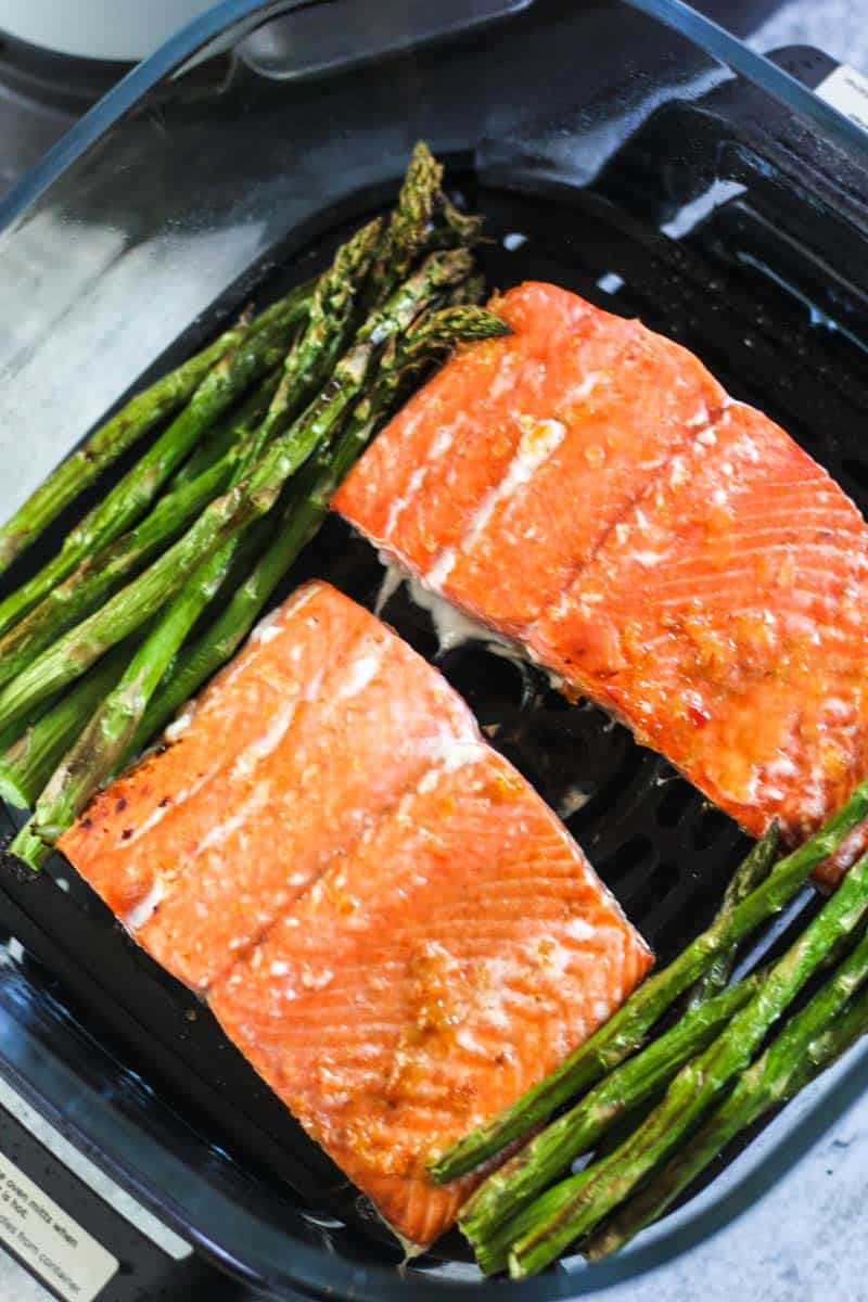two cooked salmon pieces and asparagus in ninja crispi
