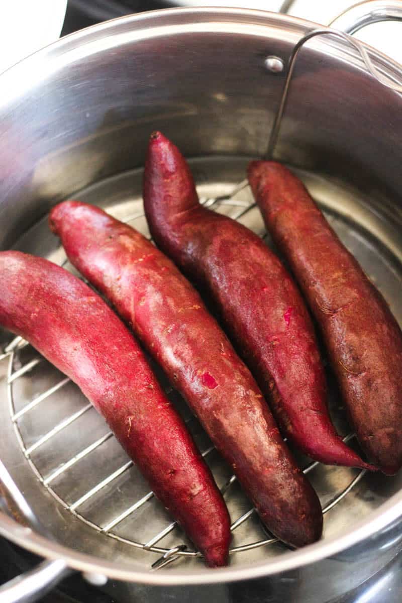 Fresh sweet potatoes steaming in a metal basket, ready for cooking or baking.