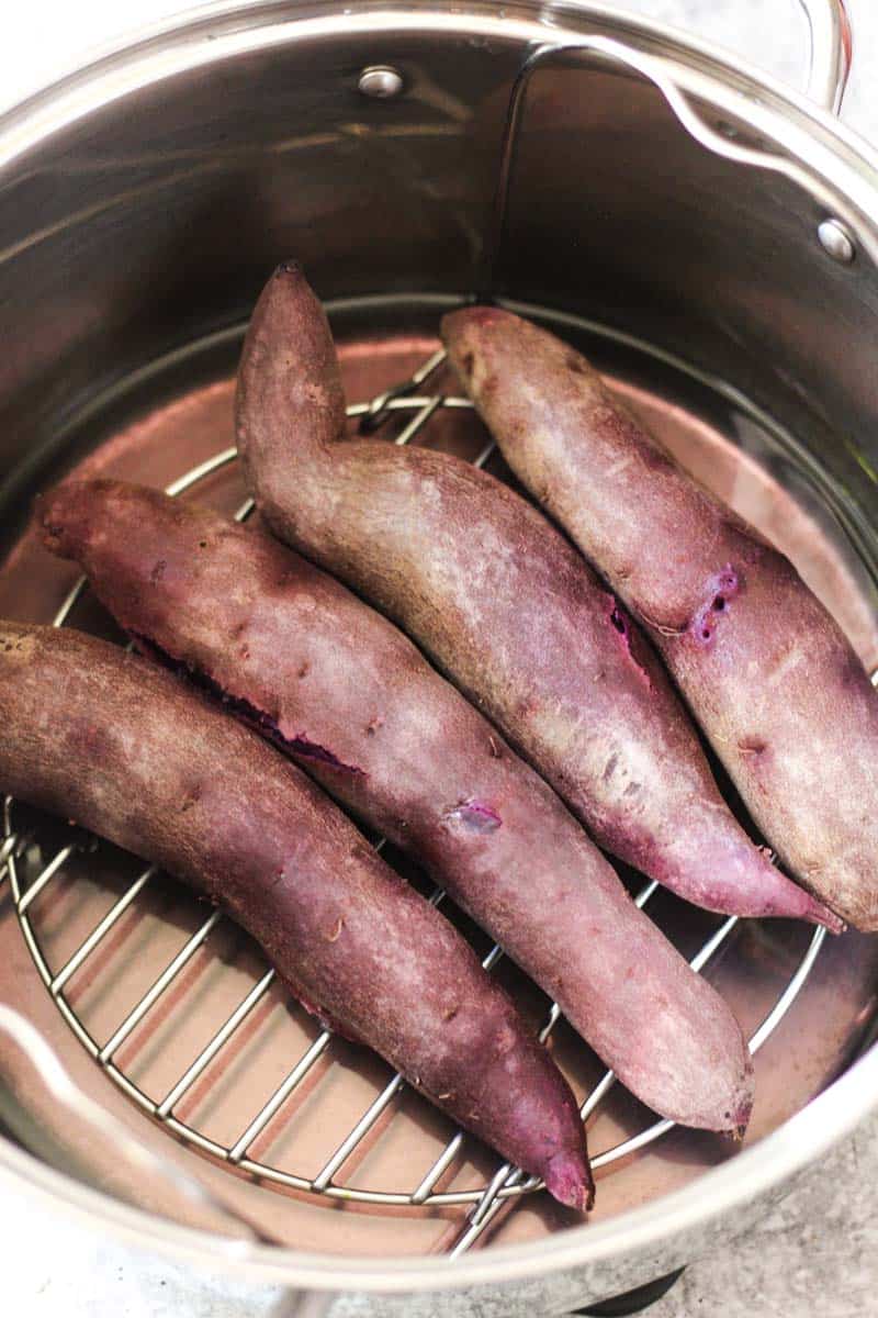 Fresh sweet potatoes steaming in a metal basket for healthy cooking.