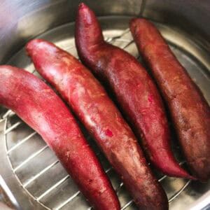 Fresh sweet potatoes steaming in a metal basket, ready for cooking or baking.