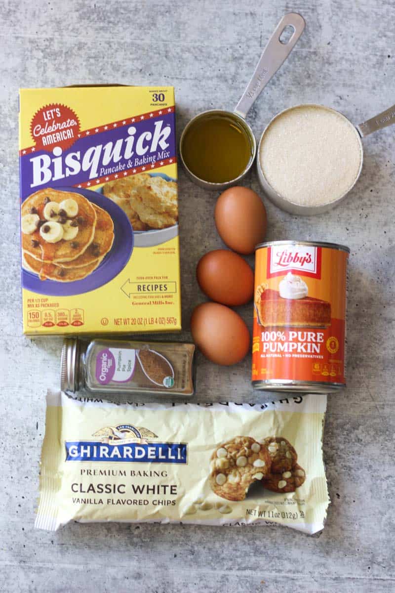 Baking ingredients including Bisquick, pumpkin, eggs, and vanilla on a gray surface.