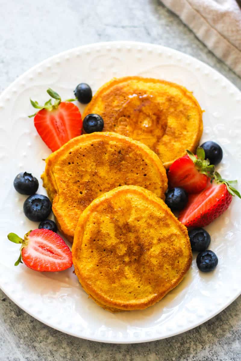 Delicious golden French toast served with strawberries and blueberries on a white plate.