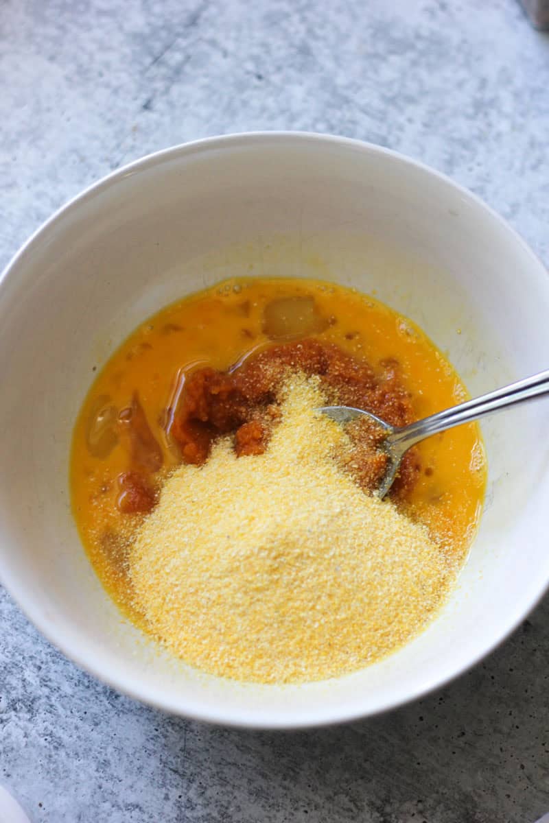 Egg mixture with spices and grated cheese in a white bowl.