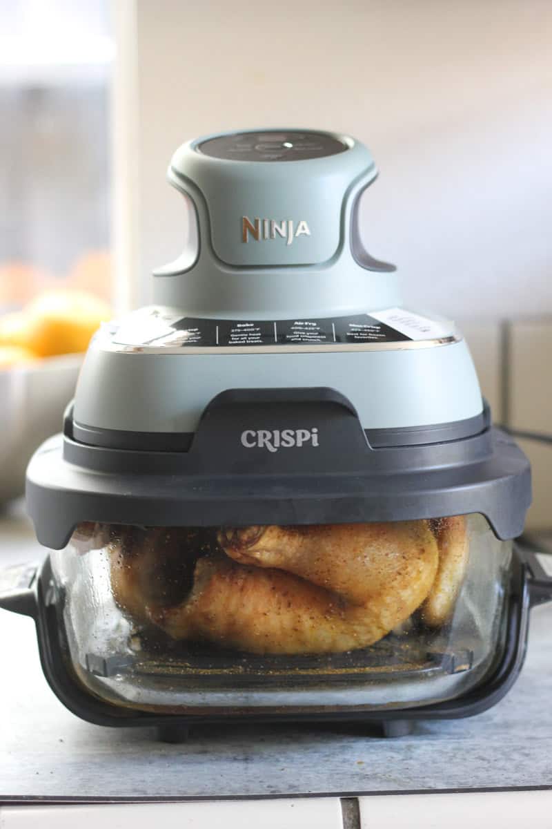 Crispi Ninja Foodi air fryer cooking chicken in a glass container.