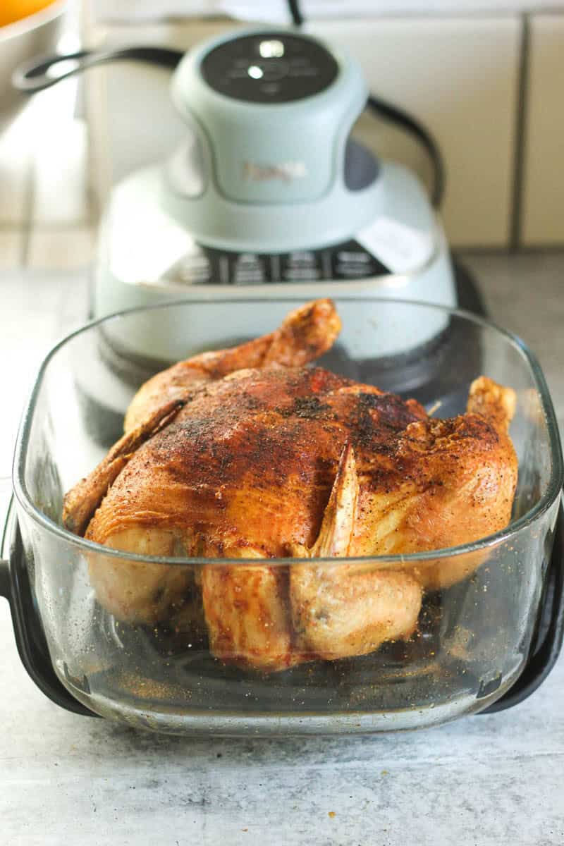 Raw seasoned chicken in a glass baking dish on a kitchen counter.