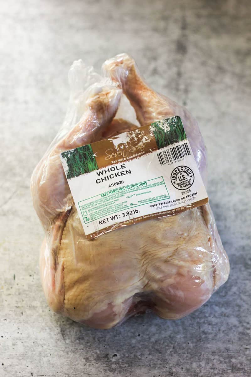 Raw whole chicken with label on a gray surface for meal preparation.