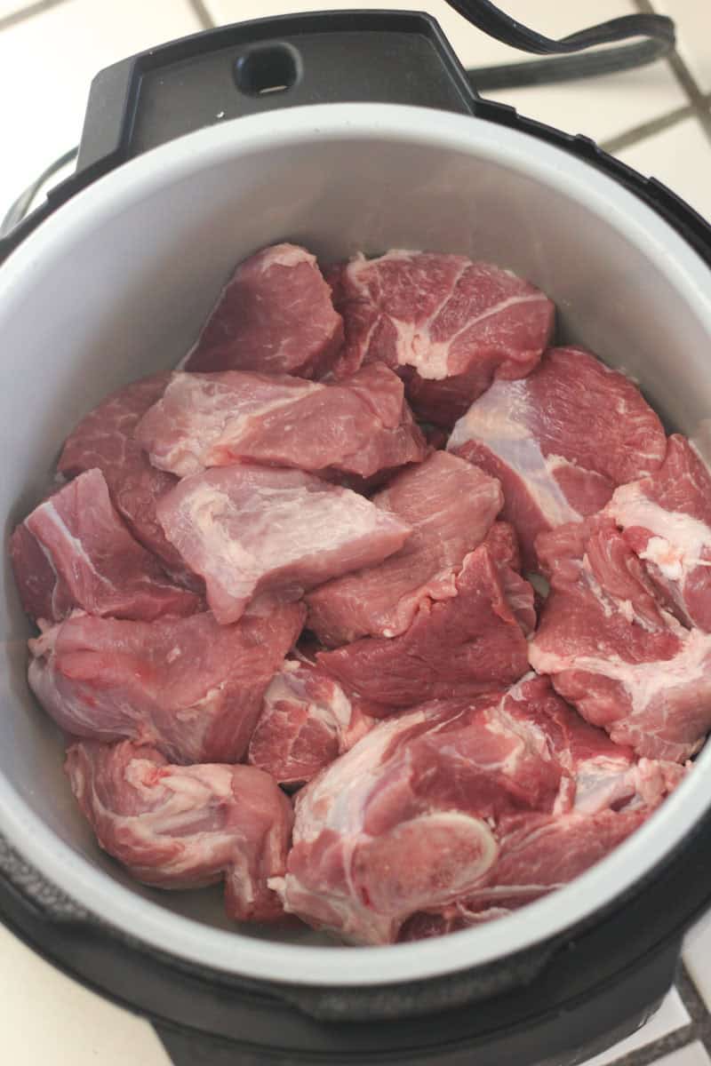 Raw meat pieces in a slow cooker ready for cooking or seasoning.